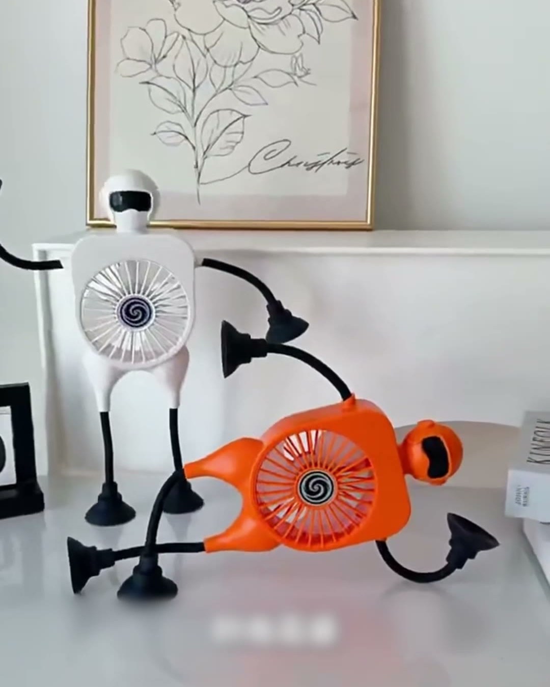 Orange and white Robot Fan units showing the flexible arms and suction-cup feet
